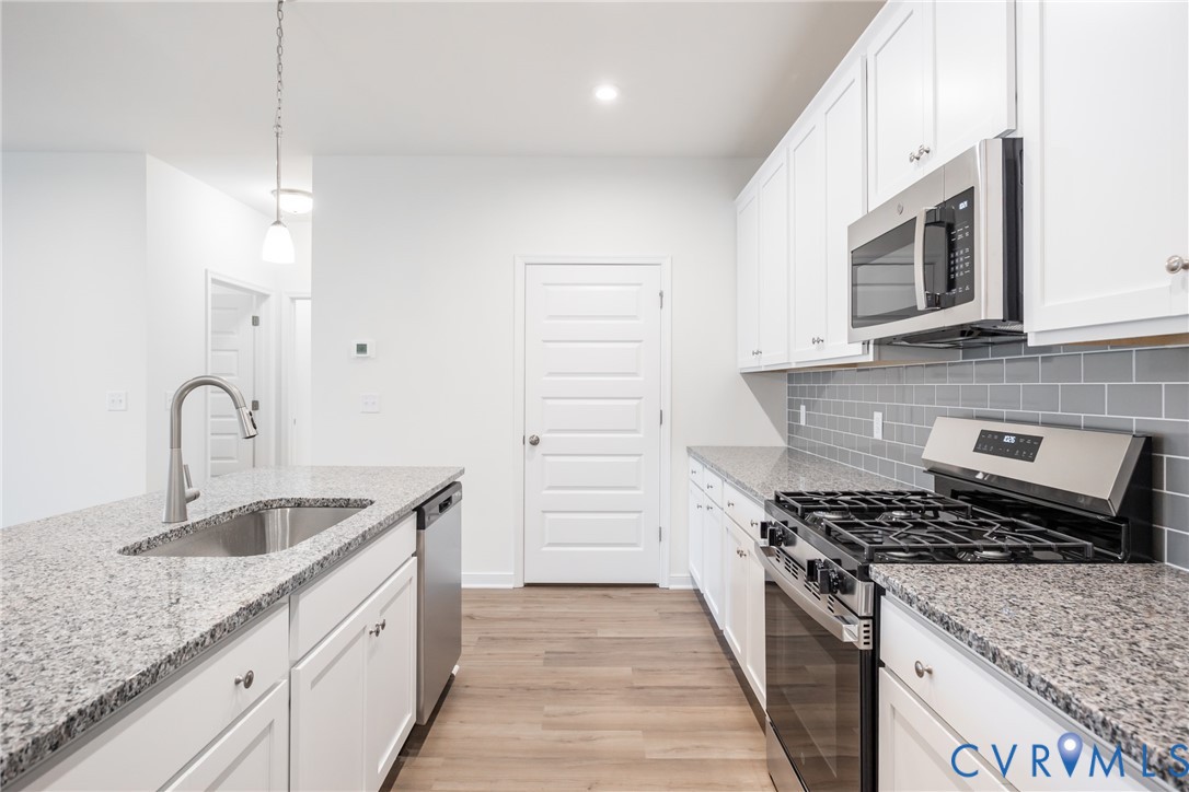 3731 Maze Runner Drive Midlothian, VA 23112 - Photo 8 of 32 a kitchen with granite countertop stainless steel appliances a stove sink and microwave