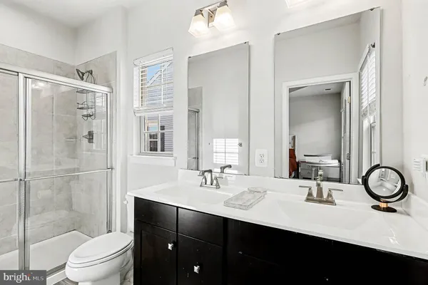 a bathroom with a sink a toilet a mirror and shower