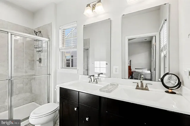 a bathroom with a sink a toilet a mirror and shower