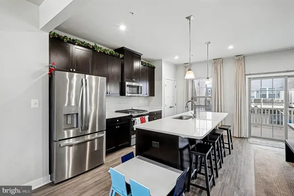 a kitchen with granite countertop a refrigerator a sink a stove a dining table and chairs