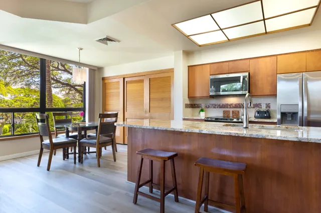 a open dining room with stainless steel appliances granite countertop furniture wooden floor and a floor to ceiling window