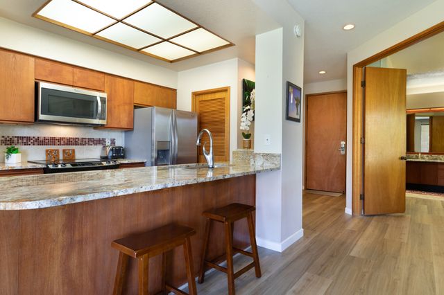 a kitchen with stainless steel appliances granite countertop a refrigerator a stove top oven a sink and dishwasher