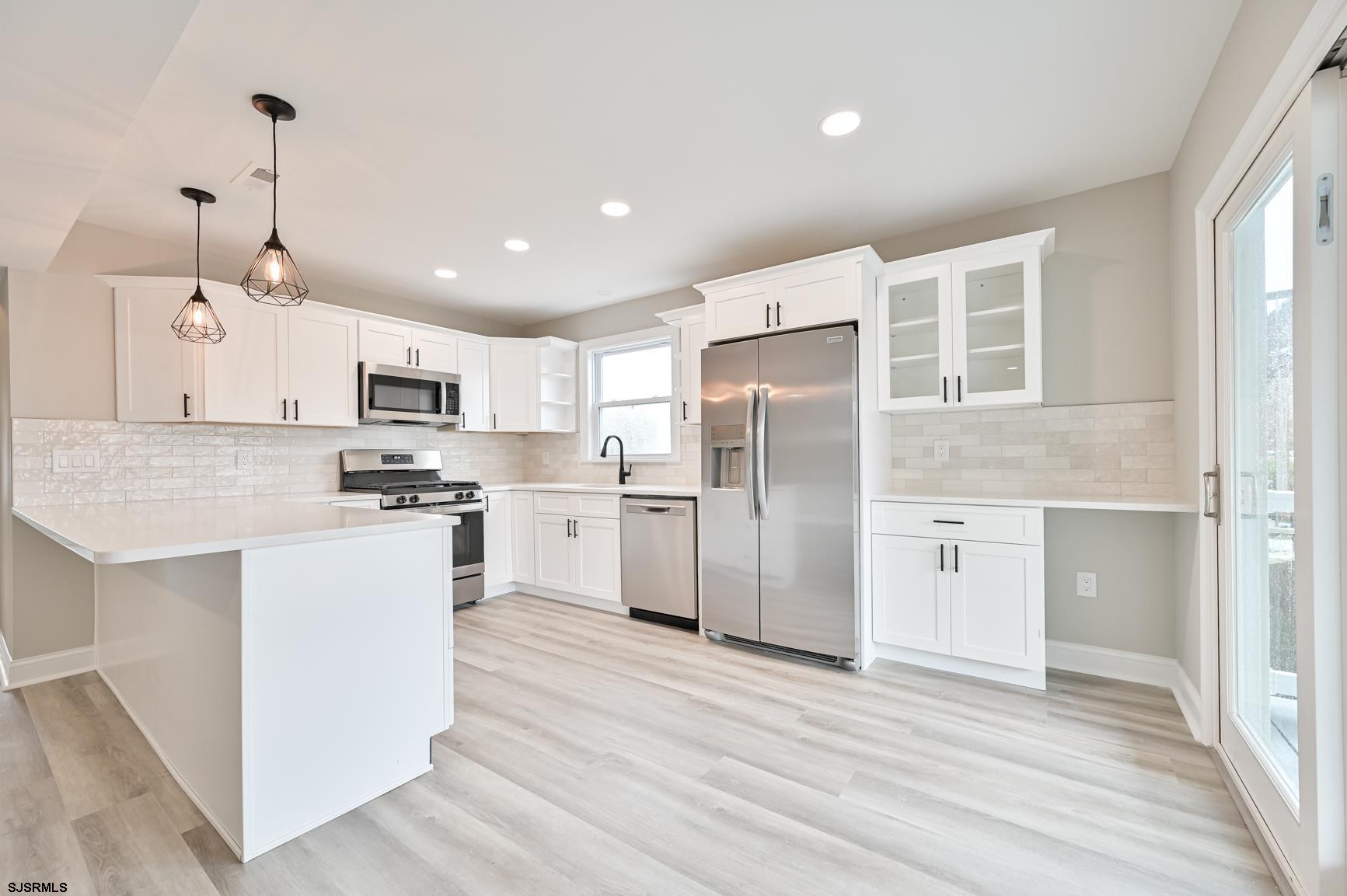 12 Lighthouse Drive, Unit A Brigantine, NJ 08203 - Photo 4 of 16 a kitchen with stainless steel appliances kitchen island granite countertop a refrigerator a sink dishwasher a stove and white cabinets with wooden floor