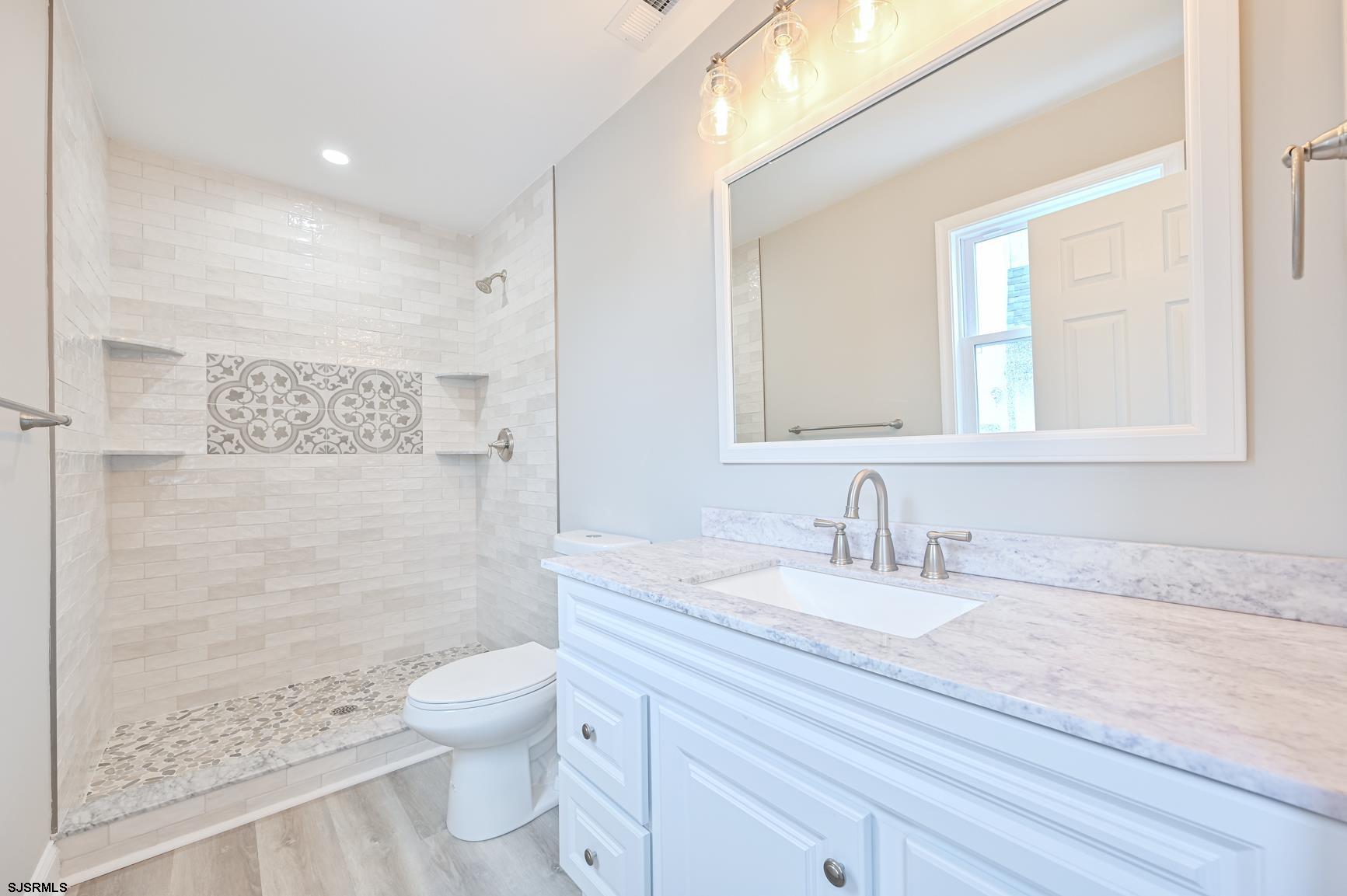 12 Lighthouse Drive, Unit A Brigantine, NJ 08203 - Photo 7 of 16 a bathroom with a granite countertop toilet a sink a mirror and a shower