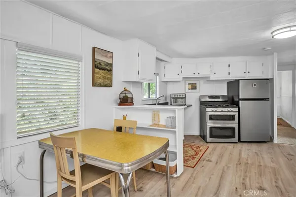 a kitchen with stainless steel appliances a stove a sink dishwasher a refrigerator with white cabinets and wooden floor