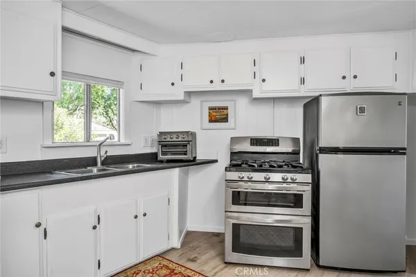 a kitchen with granite countertop white cabinets and white stainless steel appliances