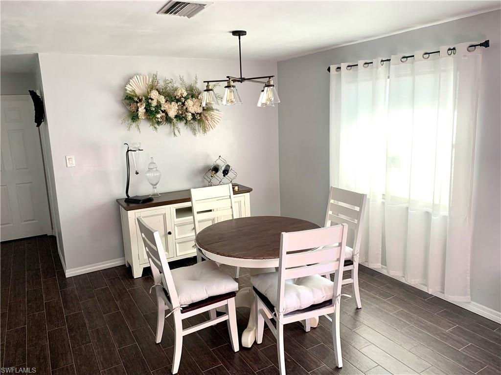 235 Cypress Way West Naples, FL 34110 - Photo 6 of 18 a dining room with furniture a chandelier and wooden floor