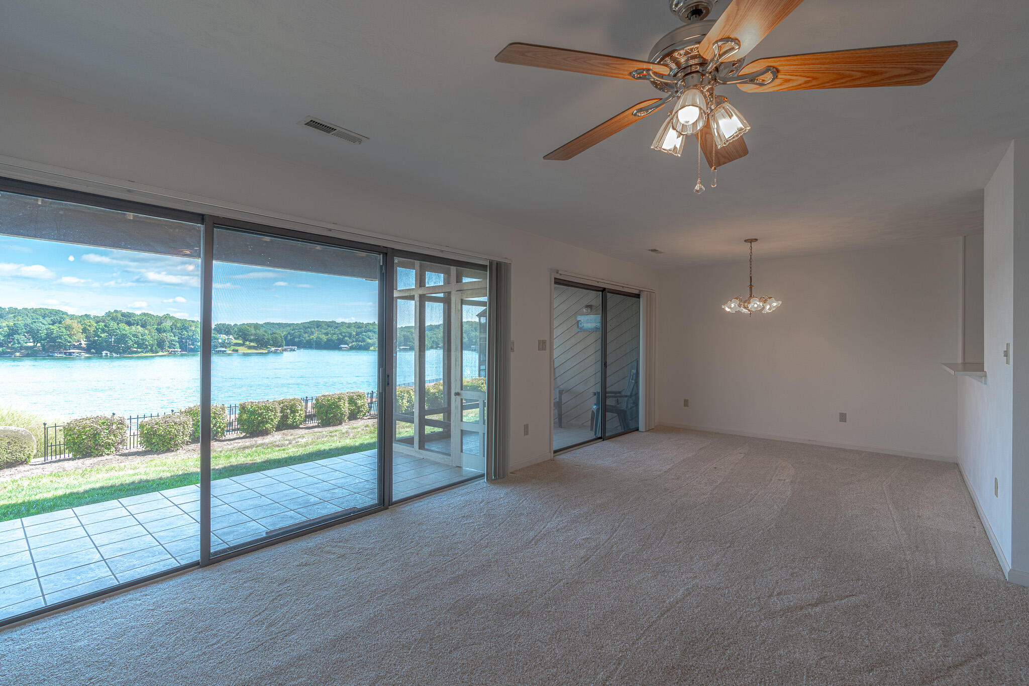 an empty room with chandelier fan large windows and an outdoor view