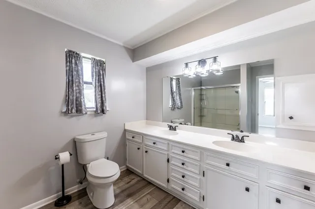 a bathroom with a toilet a double vanity sink and mirror