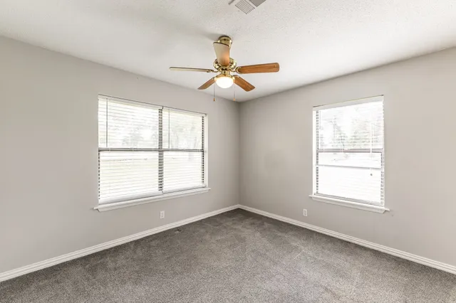 an empty room with windows and fan