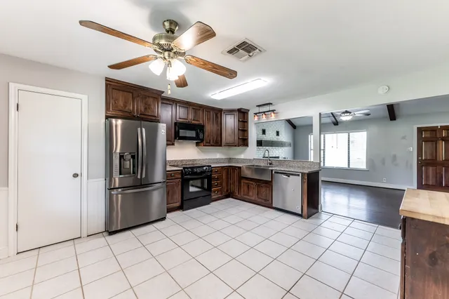 a kitchen with stainless steel appliances granite countertop a refrigerator a sink dishwasher a stove and white cabinets with wooden floor