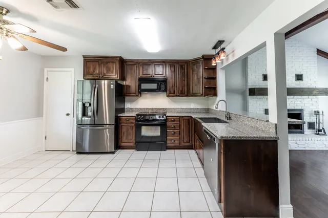 a kitchen with stainless steel appliances granite countertop a refrigerator a stove and a sink