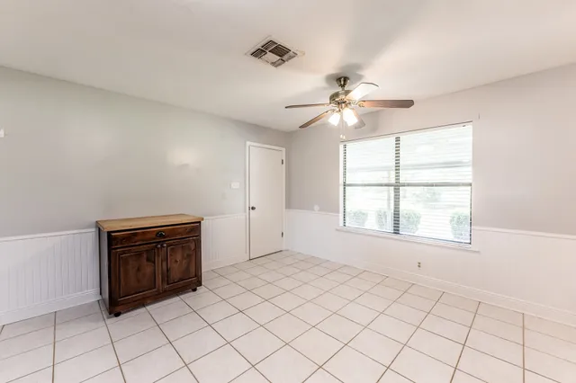 a view of an empty room with a window and a chandelier fan