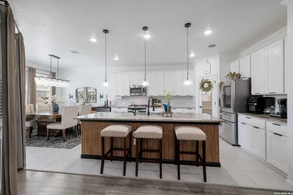 a kitchen with stainless steel appliances granite countertop a table chairs sink refrigerator and cabinets