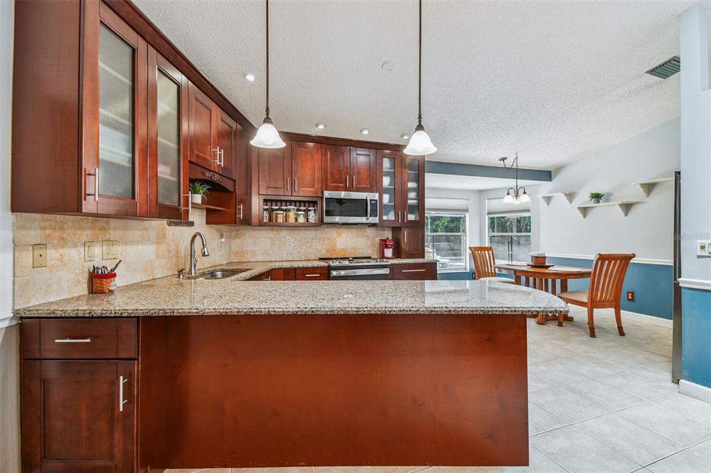 6006 Redhawk Drive New Port Richey, FL 34655 - Photo 17 of 90 a kitchen with stainless steel appliances granite countertop a sink a stove and a wooden cabinets