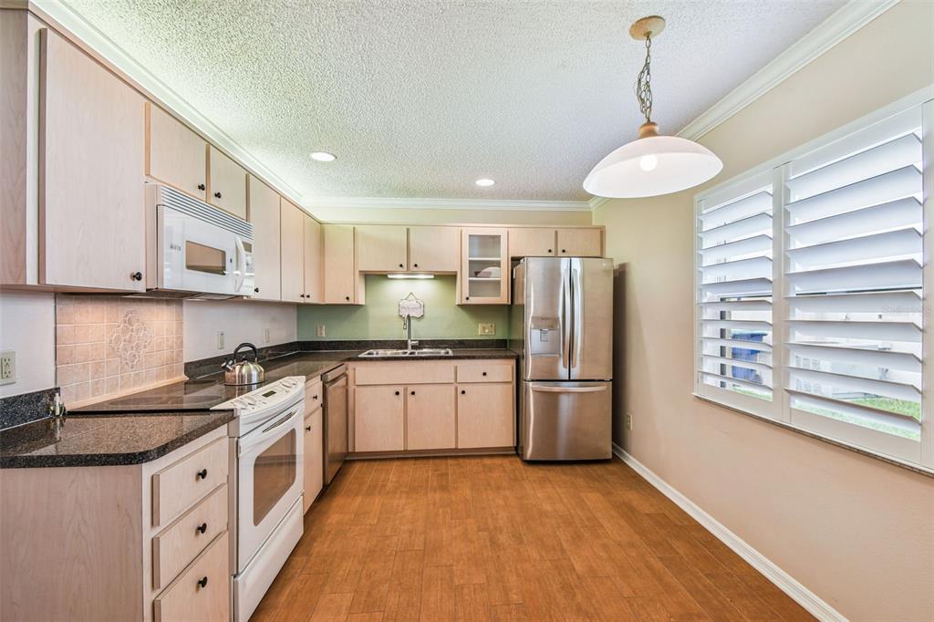 6006 Redhawk Drive New Port Richey, FL 34655 - Photo 51 of 90 a kitchen with stainless steel appliances granite countertop a refrigerator a stove and a sink with wooden floor