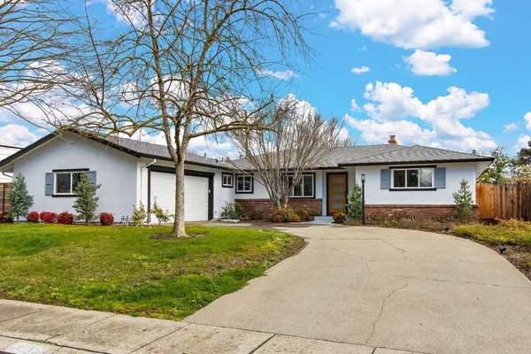 a front view of a house with a yard and trees