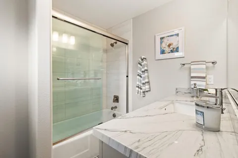 a bathroom with a sink mirror and a shower