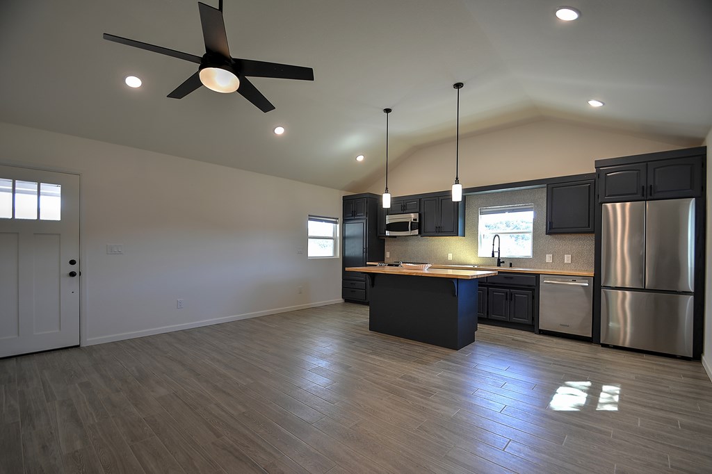 110 A Garner Road Kerrville, TX 78028 - Photo 6 of 46 a large kitchen with a center island wooden floor stainless steel appliances and cabinets