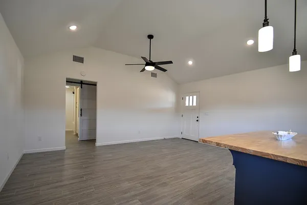 a view of an empty room with wooden floor and a ceiling fan