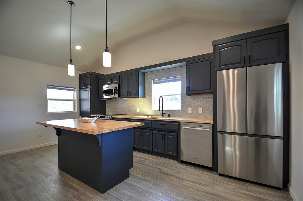 110 A Garner Road Kerrville, TX 78028 - Photo 10 of 46 a kitchen with stainless steel appliances granite countertop a refrigerator a sink dishwasher a kitchen island with wooden cabinets and floor