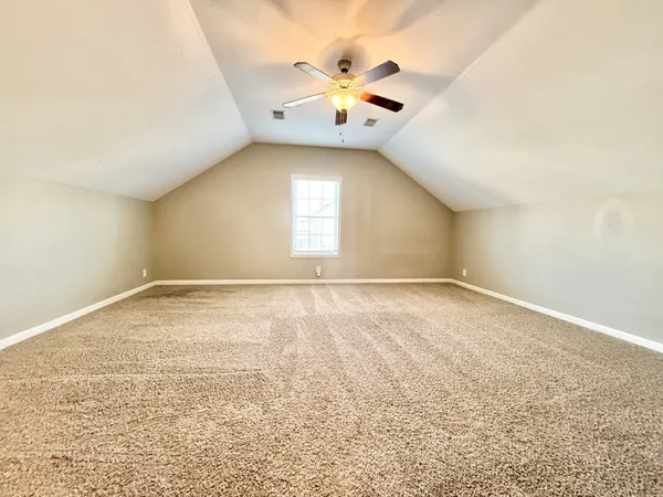 an empty room with a chandelier fan and windows