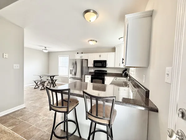 a kitchen with kitchen island a dining table chairs stainless steel appliances and cabinets