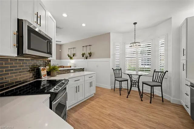 a kitchen with stainless steel appliances a sink a stove a table and chairs