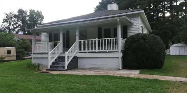 a view of a house with a yard and a large tree
