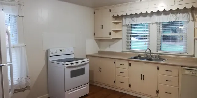 a kitchen with granite countertop white cabinets and white appliances