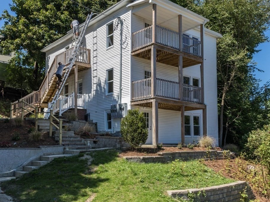 a view of a white house with a yard and plants