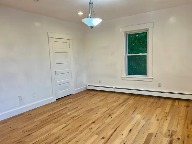 an empty room with wooden floor cabinet and windows