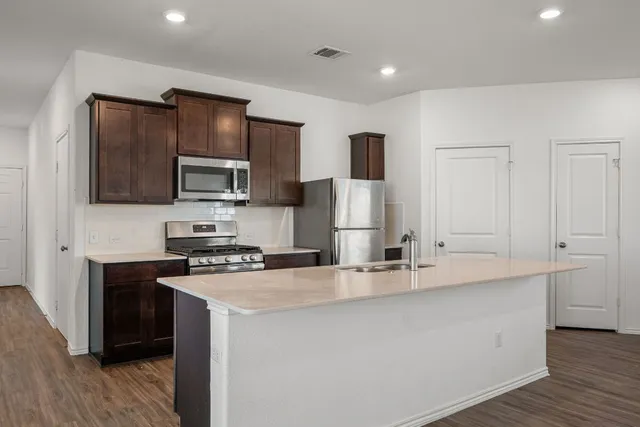 a kitchen with kitchen island a sink stainless steel appliances and cabinets
