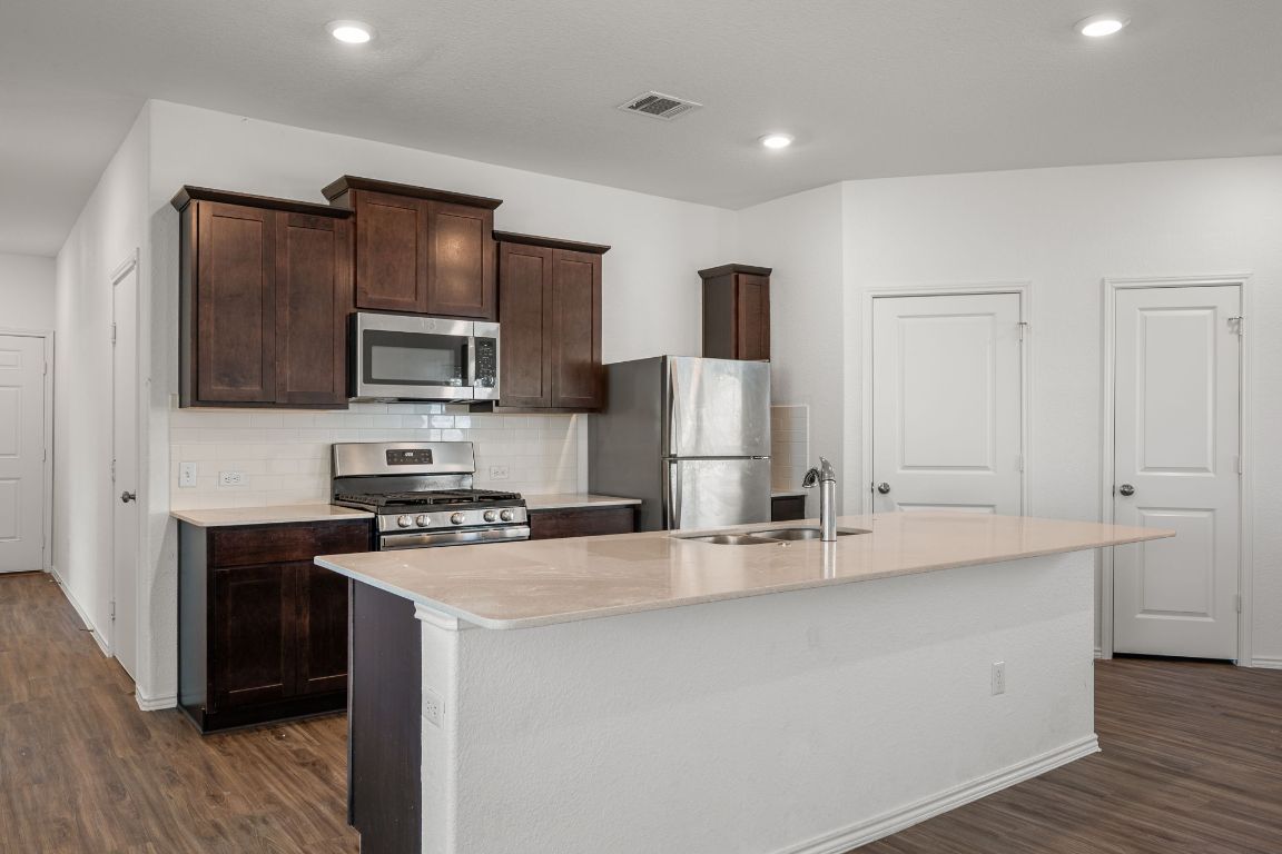 3206 Dusted Daisey Street Pflugerville, TX 78660 - Photo 7 of 25 a kitchen with kitchen island a sink stainless steel appliances and cabinets