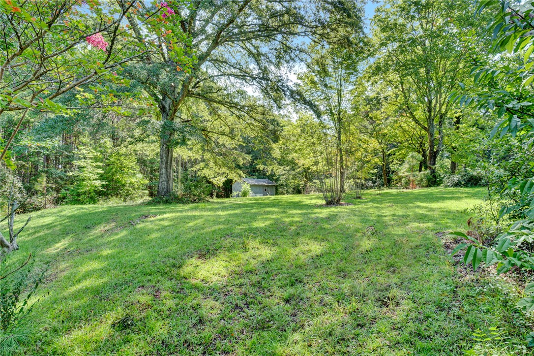 1506 Park Ridge Drive Seneca, SC 29672 - Photo 2 of 4 Mature trees frame a grassy lawn leading toward a detached storage shed nestled in the woods.