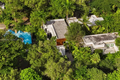 an aerial view of a house with a yard lake and trees all around