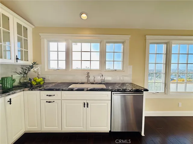 a kitchen with granite countertop a sink and a white wooden cabinets