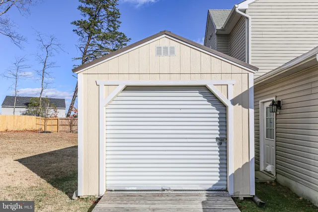 a white building with a white roof and wooden fence