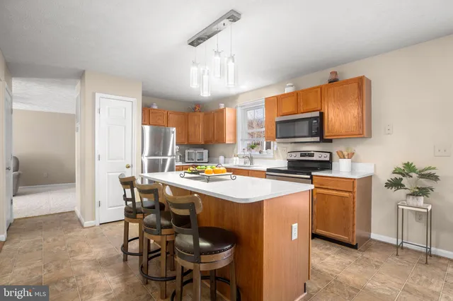 a kitchen with stainless steel appliances a stove a sink dishwasher a refrigerator a microwave oven with white cabinets and wooden floor