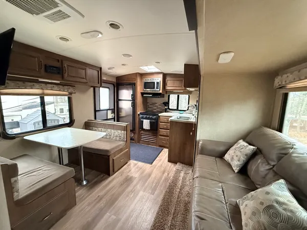 a kitchen with stainless steel appliances granite countertop a refrigerator a sink dishwasher a stove and a dining table with wooden floor