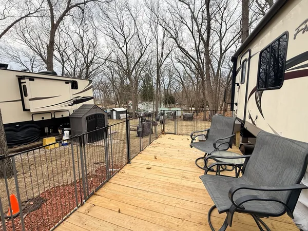 a view of a patio with table and chairs with wooden floor and fence