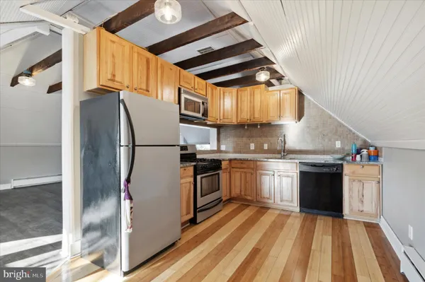 a kitchen with stainless steel appliances granite countertop a refrigerator a stove and a sink with wooden floor