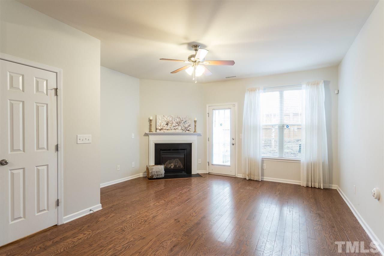 3106 Berkeley Springs Place Raleigh, NC 27616 - Photo 11 of 26 an empty room with wooden floor fireplace and windows