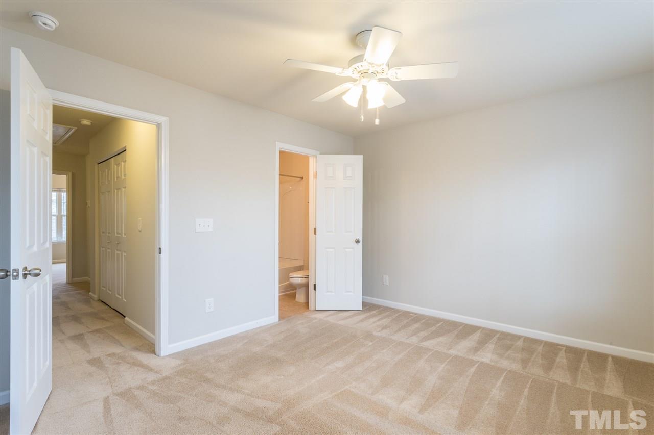 3106 Berkeley Springs Place Raleigh, NC 27616 - Photo 21 of 26 an empty room with a chandelier fan and a bathroom