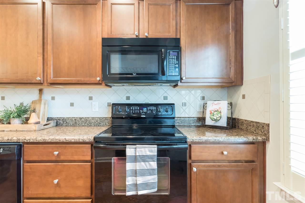 3106 Berkeley Springs Place Raleigh, NC 27616 - Photo 8 of 26 a kitchen with granite countertop a stove top oven microwave and cabinets