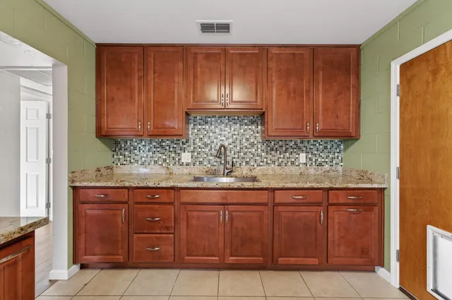 a kitchen with granite countertop a refrigerator and a stove top oven