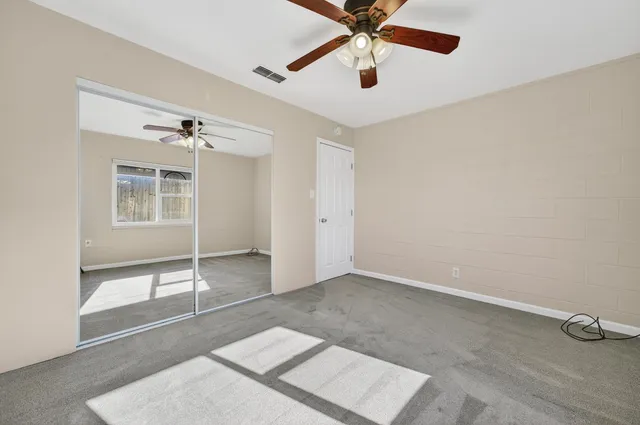 an empty room with windows and fan