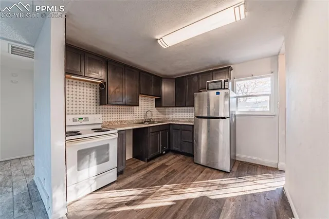 a kitchen with granite countertop a refrigerator stove and sink