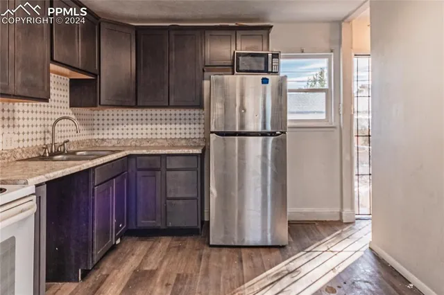 a white refrigerator freezer sitting inside of a kitchen with stainless steel appliances wooden floor
