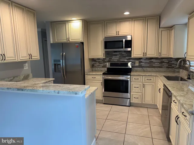 a kitchen with kitchen island granite countertop a stove sink and refrigerator